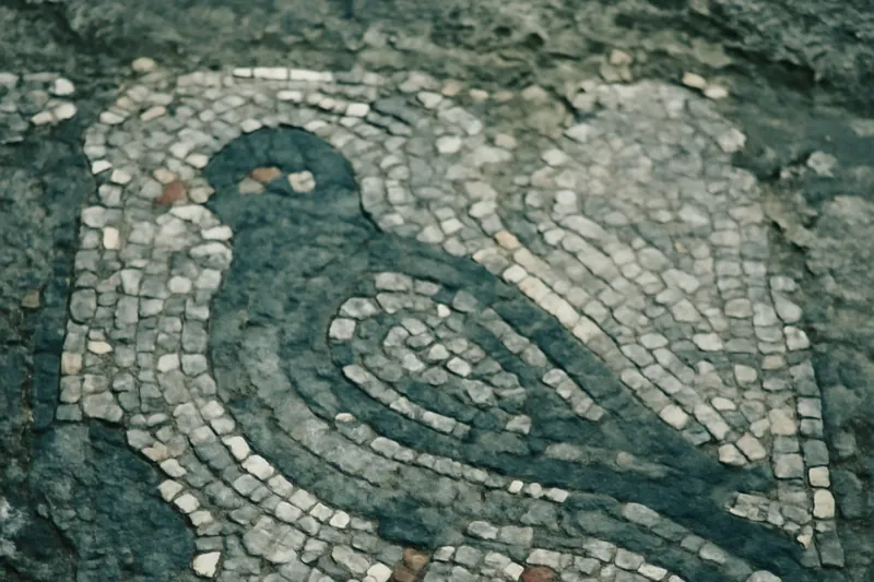 Fragment de mosaïque romaine figurant un oiseau avec des tesselles colorées.