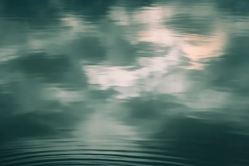 Eau calme sous un ciel nuageux, traversée de fines ondulations régulières.